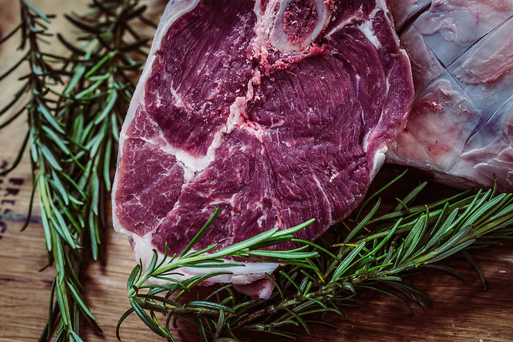 Rohes Rindersteak mit Rosmarin und Knoblauch neben perfekt medium gegrilltem Steak, aufgeschnitten mit saftigem Kern